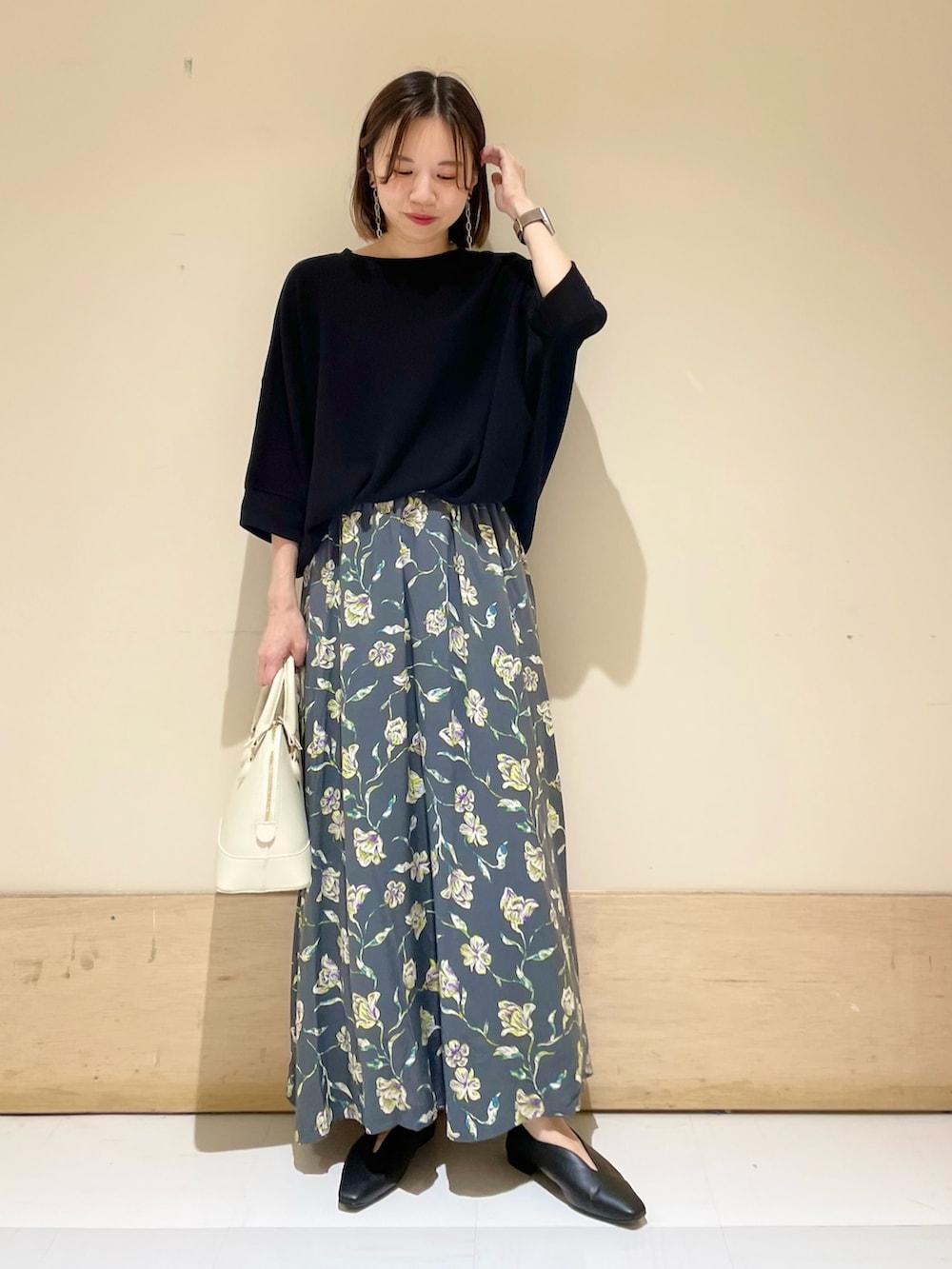 グレー系のスカート、ホワイト系のショルダーバッグ、ブラック系のパンプスを着用したレディースの秋コーディネートの3枚目の写真