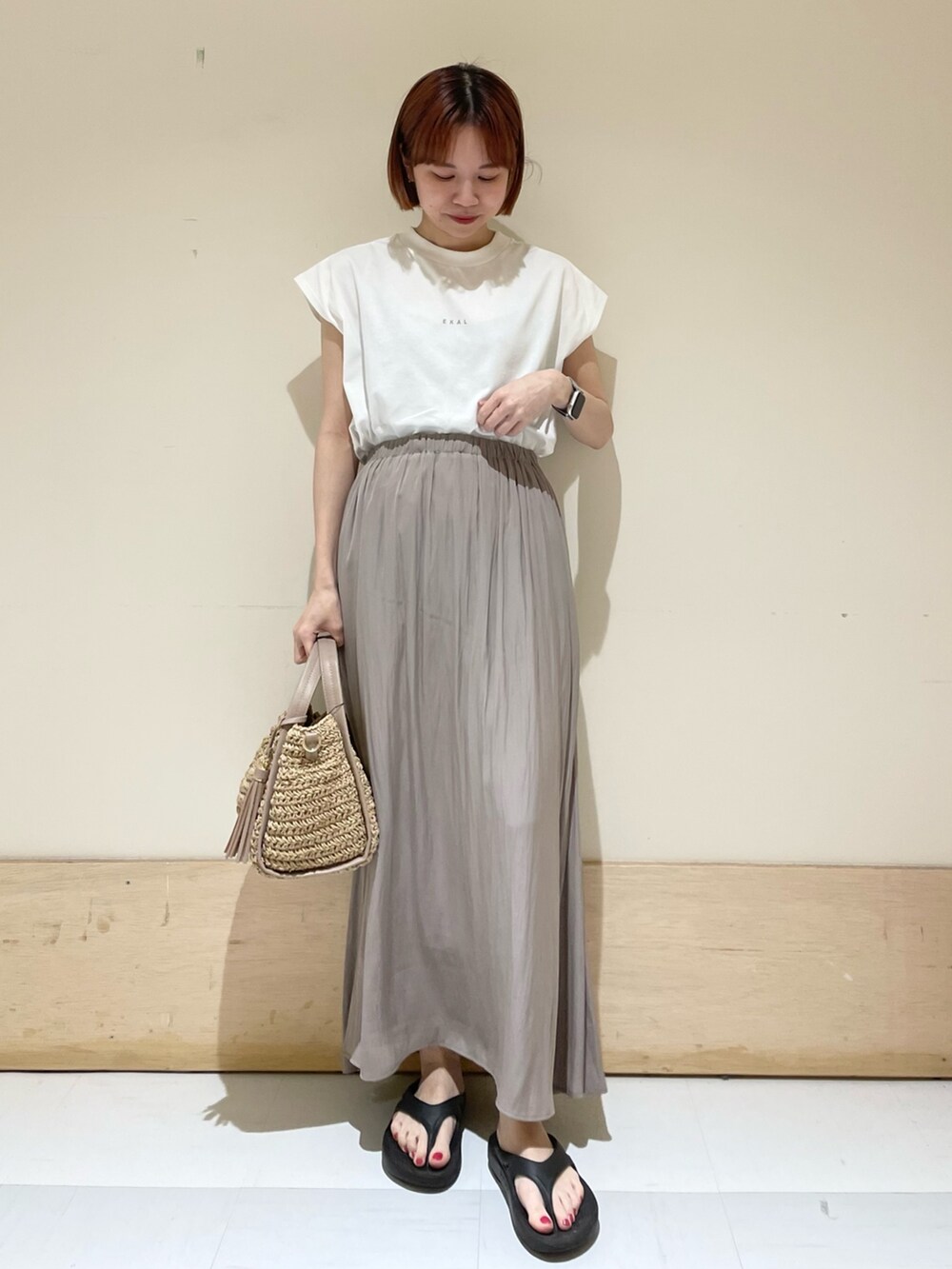 グレー系のスカート、ホワイト系のTシャツ/カットソー、ベージュ系のかごバッグを着用したレディースの春コーディネートの3枚目の写真