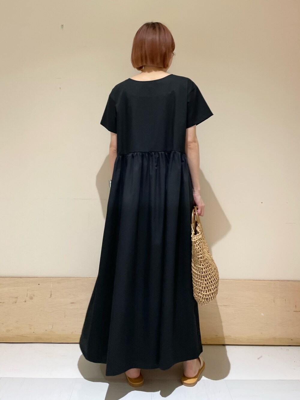 ホワイト系のサンダル、ベージュ系のかごバッグ、ブラック系のワンピースを着用したレディースの春コーディネートの7枚目の写真