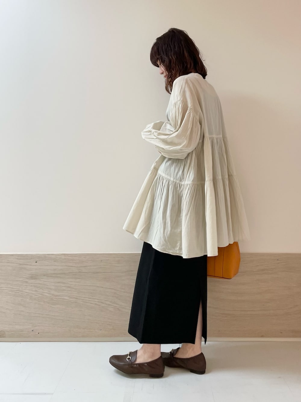 ブラック系のスカート、ホワイト系のチュニックを着用したレディースの春コーディネートの6枚目の写真