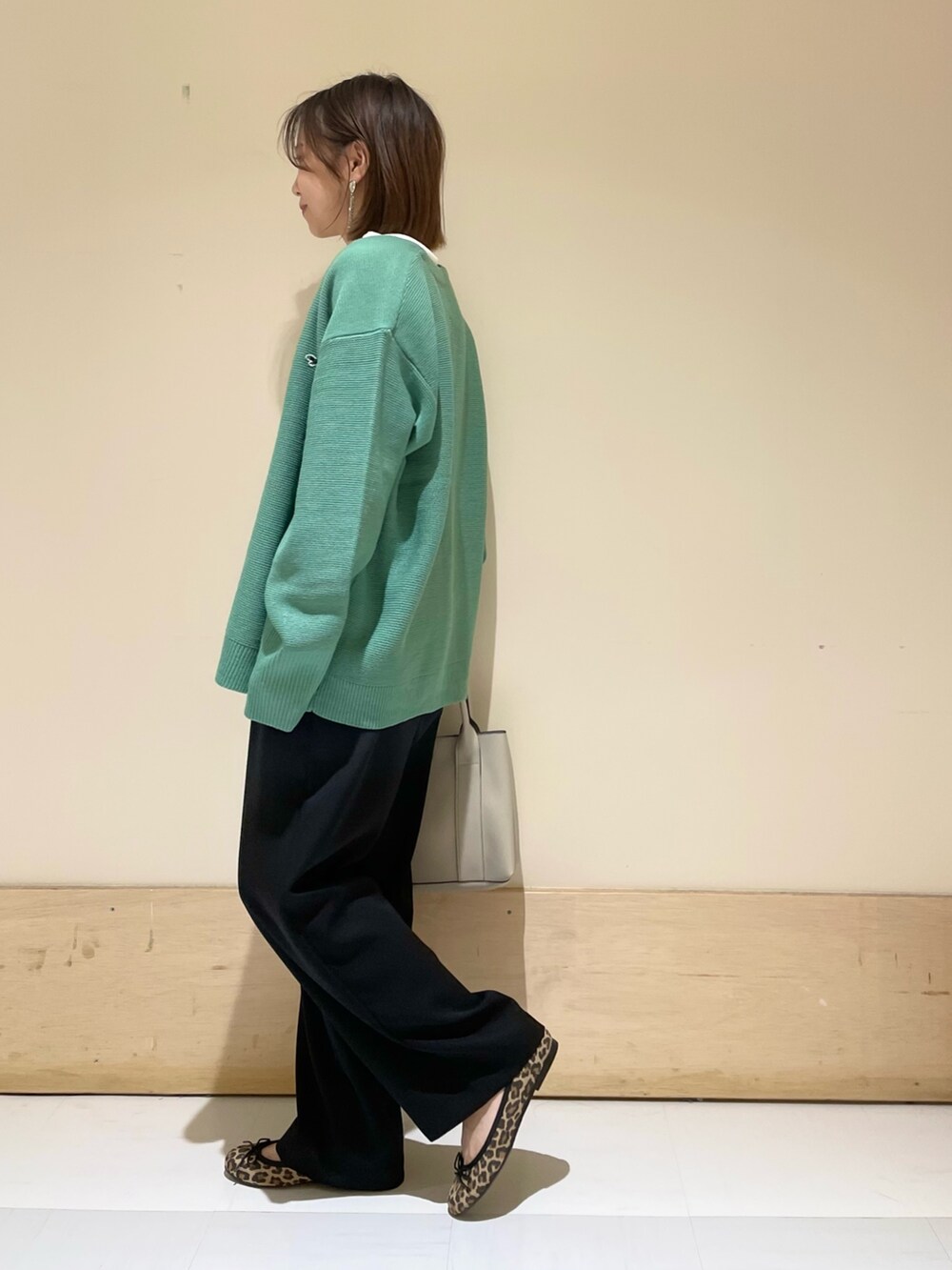 グリーン系のカーディガン/ボレロ、ホワイト系のTシャツ/カットソー、グレー系のトートバッグを着用したレディースの秋コーディネートの4枚目の写真