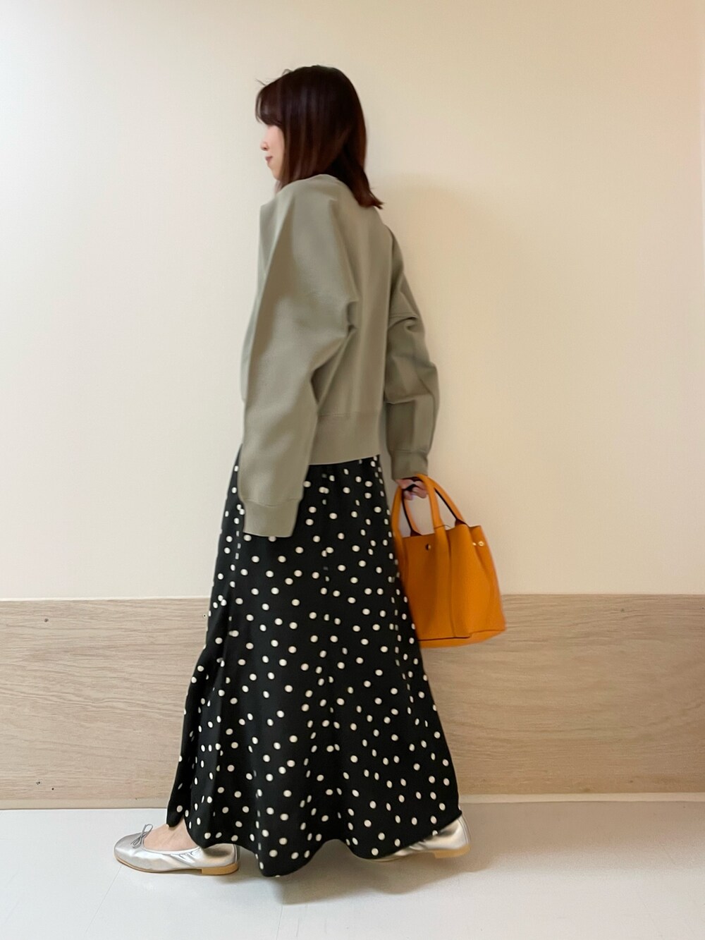 ブラック系のスカート、シルバー系のバレエシューズ、グリーン系のニット/セーターを着用したレディースの春コーディネートの5枚目の写真