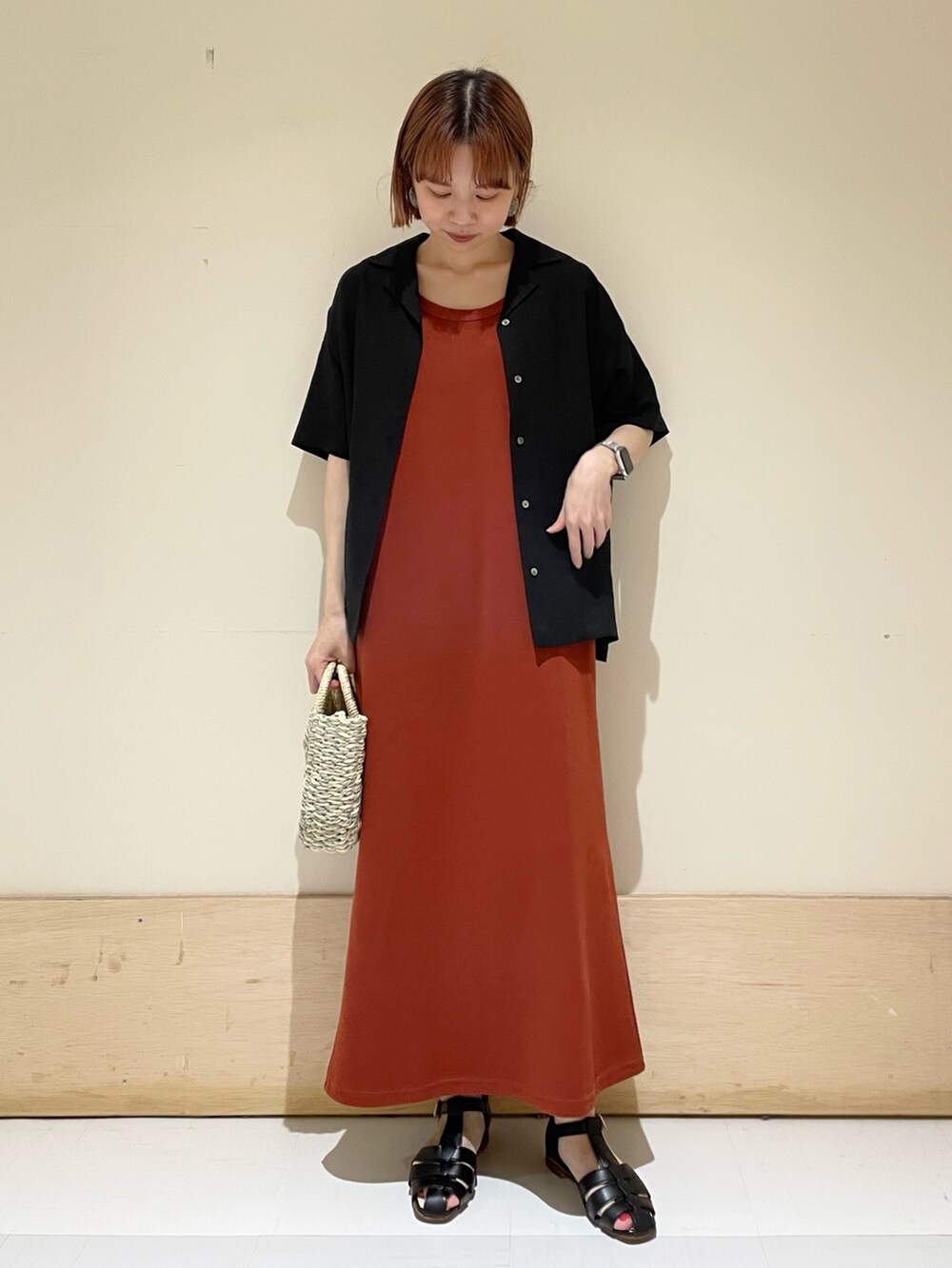 オレンジ系のワンピース、グレー系のかごバッグ、ブラック系のシャツ/ブラウスを着用したレディースの春コーディネートの2枚目の写真