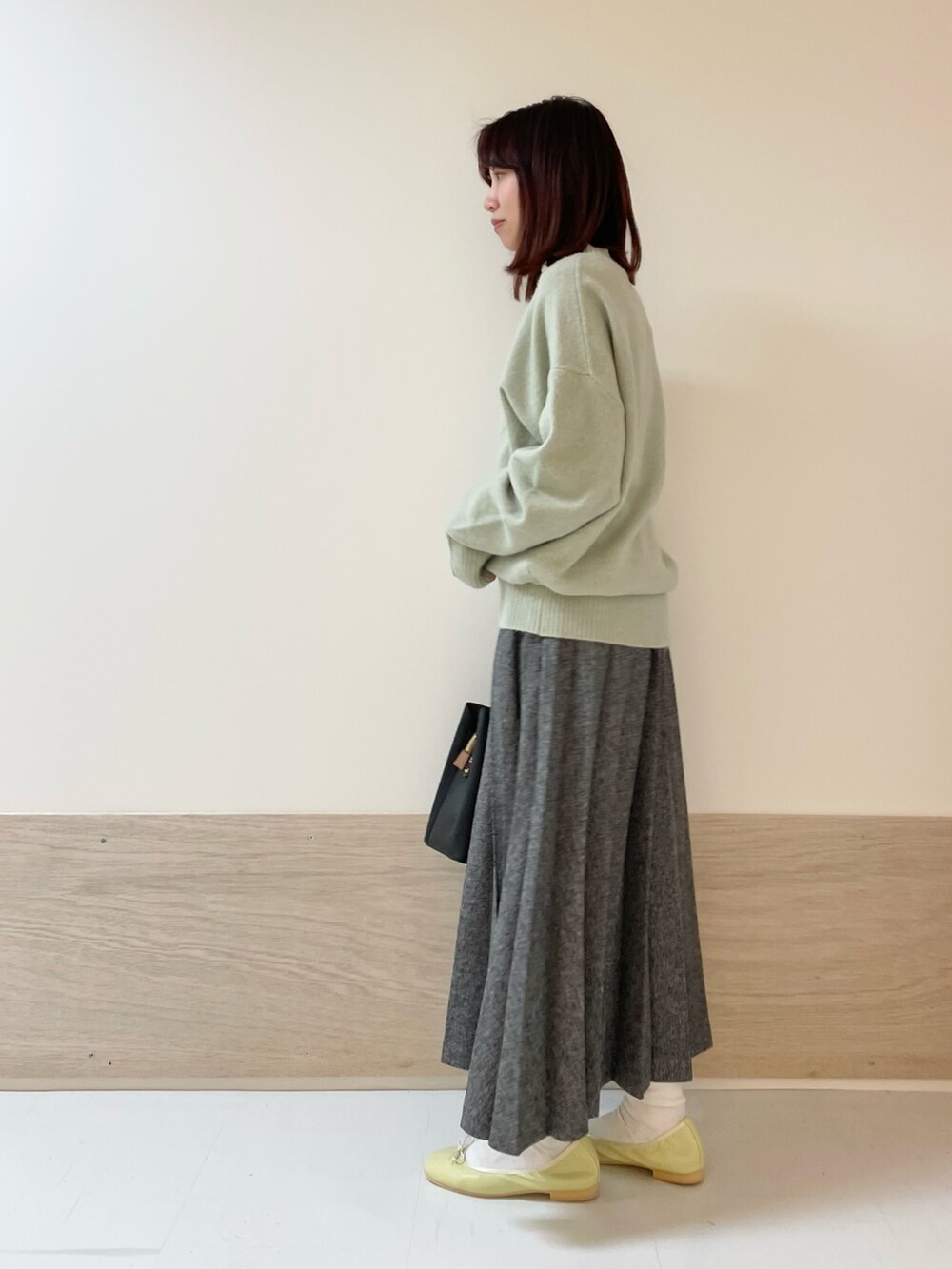 グリーン系のニット/セーター、イエロー系のバレエシューズ、ブルー系のスカートを着用したレディースの冬コーディネートの4枚目の写真