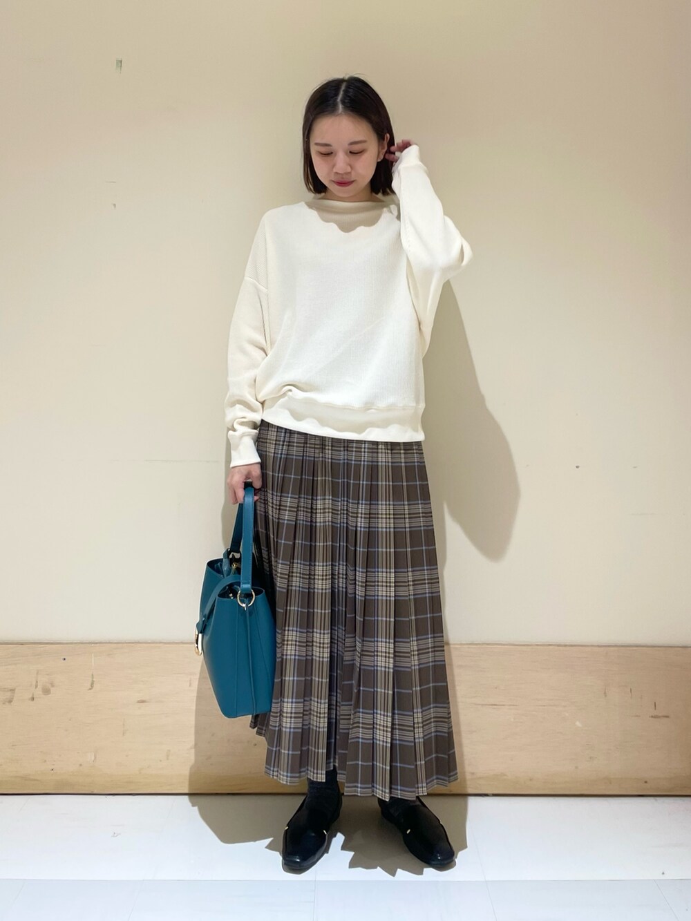 ブルー系のハンドバッグ、ブラック系のローファー、ベージュ系のTシャツ/カットソーを着用したレディースの秋コーディネートの3枚目の写真