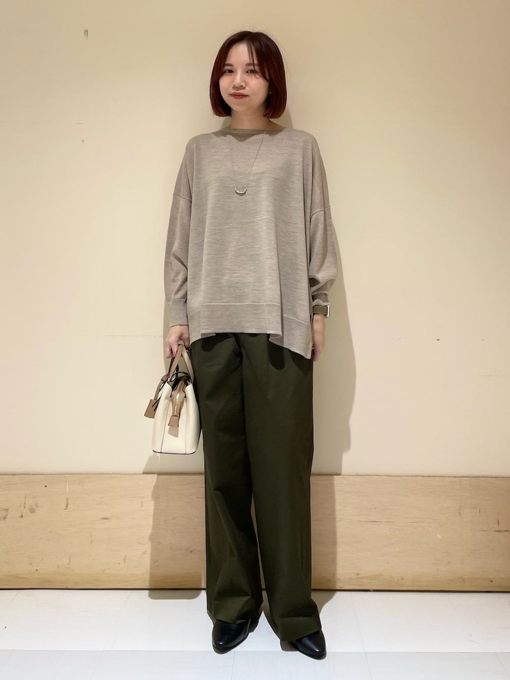 ブラック系のパンプス、ベージュ系のニット/セーター、ホワイト系のハンドバッグを着用したレディースの秋コーディネートの2枚目の写真