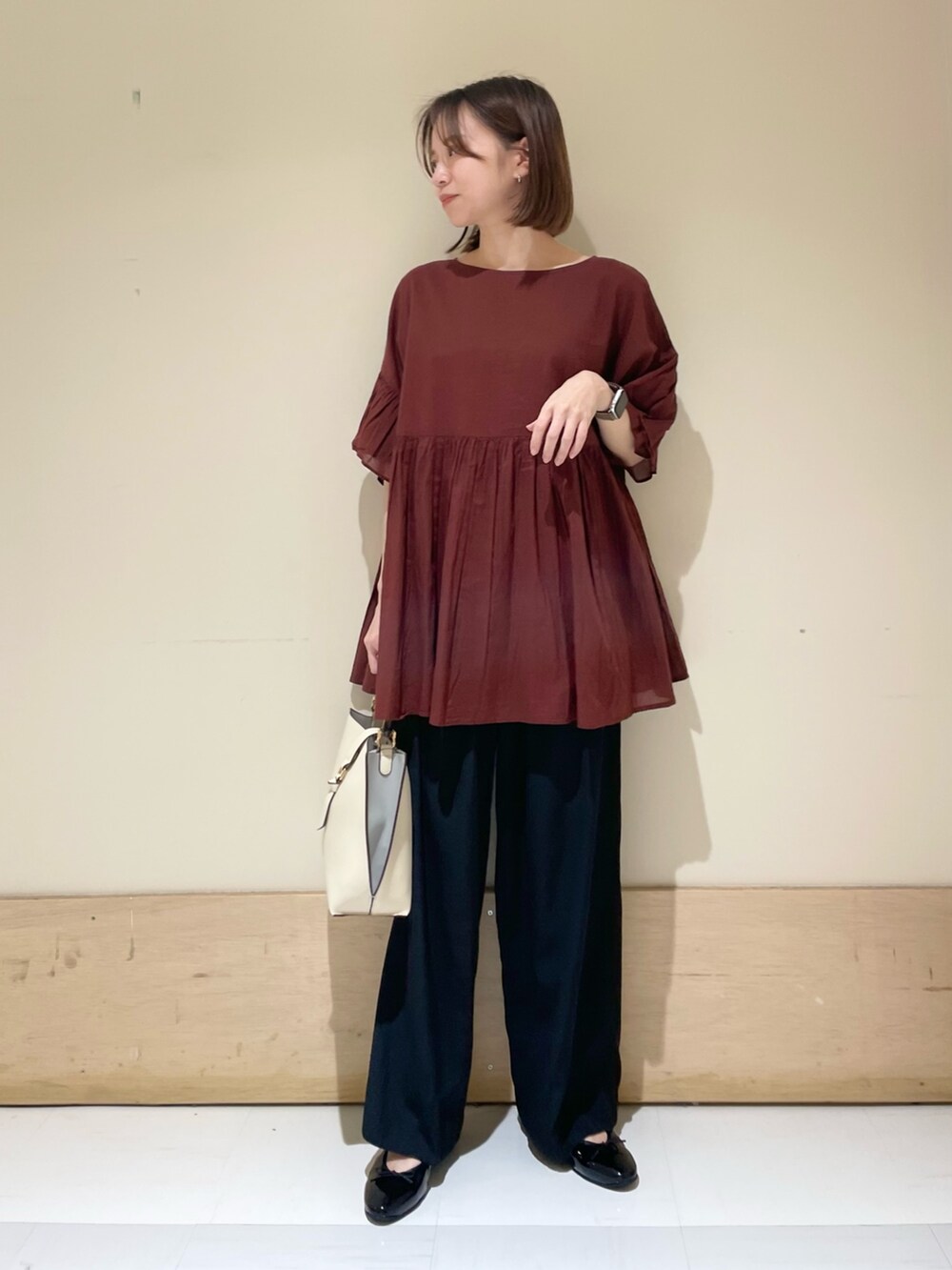 レッド系のシャツ/ブラウス、ブラック系のその他パンツ、ホワイト系のハンドバッグを着用したレディースの秋コーディネートの3枚目の写真