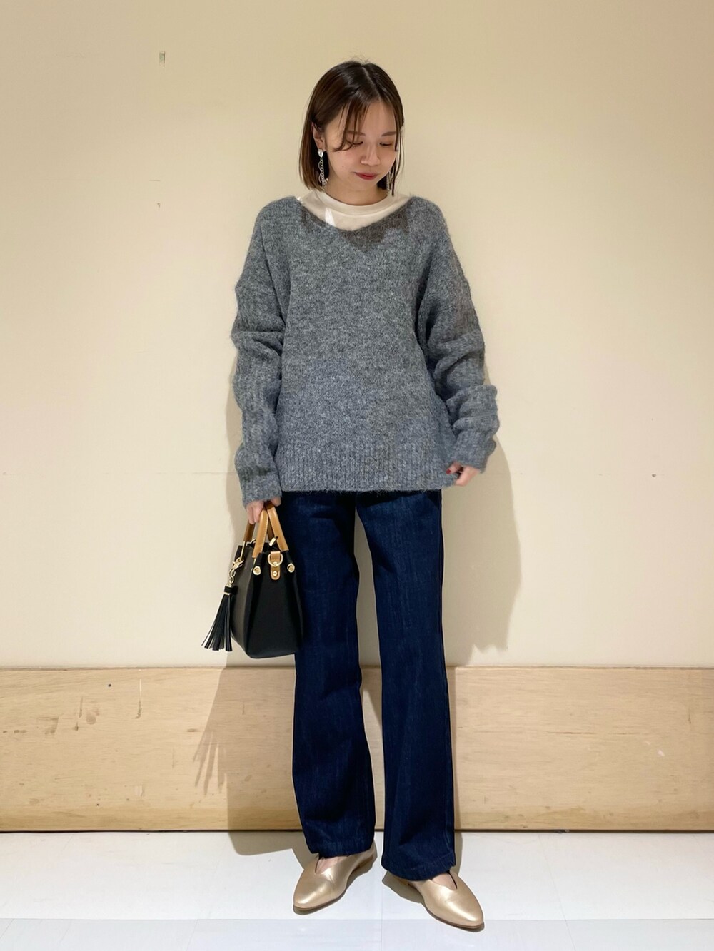 ゴールド系のパンプス、ブラック系のトートバッグ、ブルー系のデニムパンツを着用したレディースの秋コーディネートの2枚目の写真