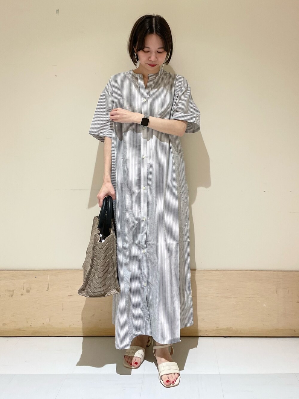 ベージュ系のトートバッグ、ホワイト系のサンダル、ブラック系のワンピースを着用したレディースの夏コーディネートの2枚目の写真