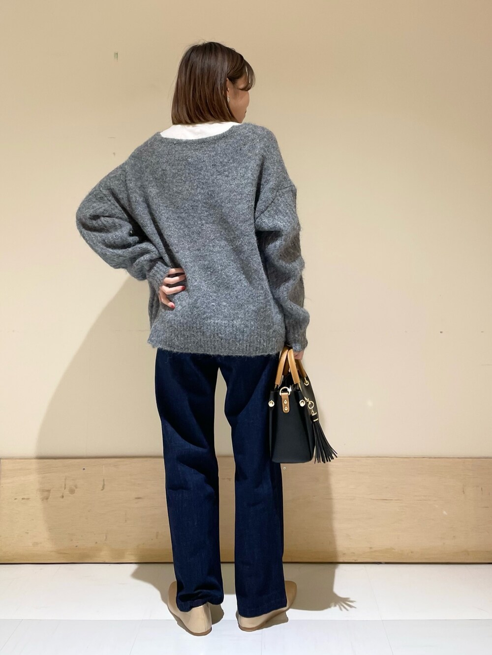 ゴールド系のパンプス、ブラック系のトートバッグ、ブルー系のデニムパンツを着用したレディースの秋コーディネートの5枚目の写真