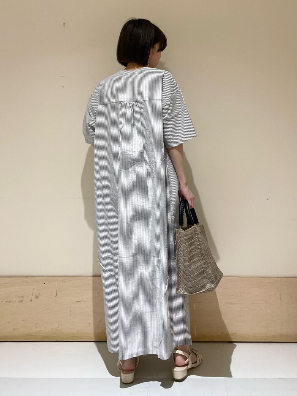 ベージュ系のトートバッグ、ホワイト系のサンダル、ブラック系のワンピースを着用したレディースの夏コーディネートの6枚目の写真