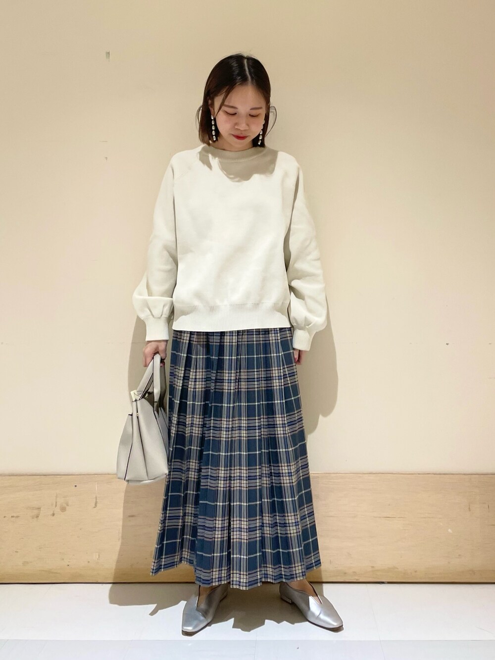 ホワイト系のニット/セーター、グレー系のトートバッグ、ブルー系のスカートを着用したレディースの秋コーディネートの2枚目の写真