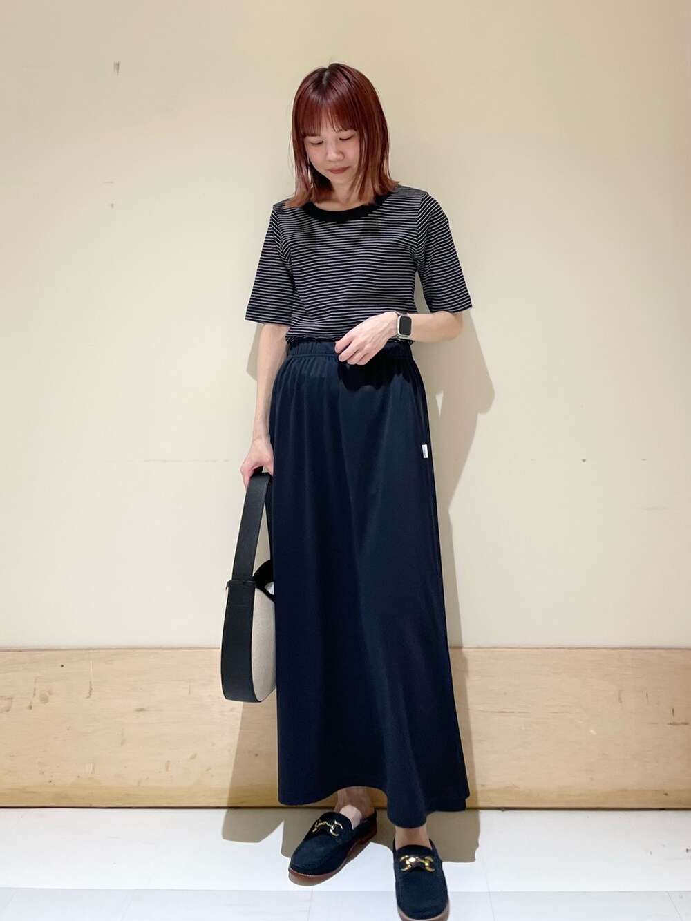 ブルー系のその他シューズ、ブルー系のスカート、ブラック系のハンドバッグを着用したレディースの春コーディネートの3枚目の写真