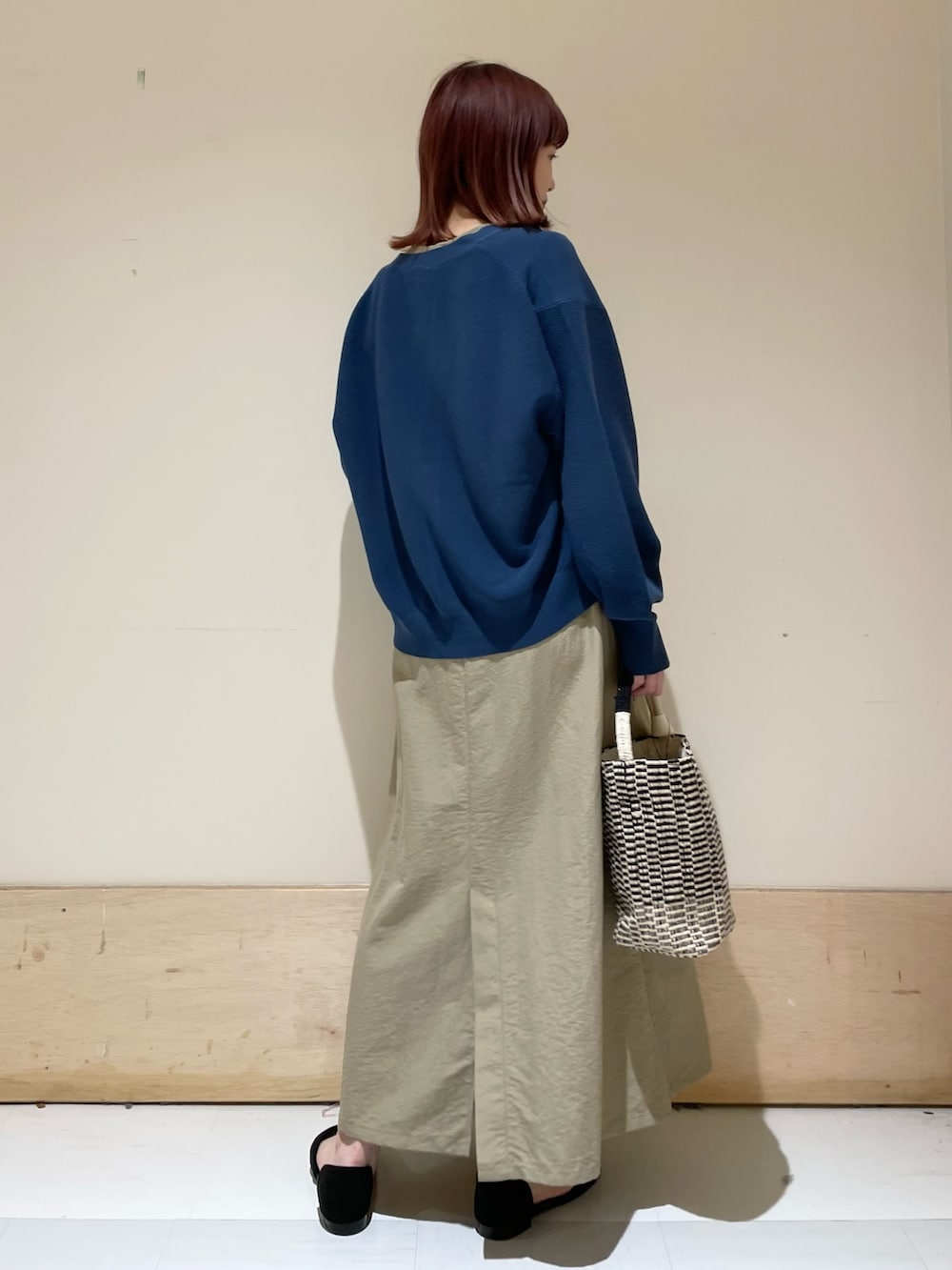 ベージュ系のワンピース、ブルー系のニット/セーター、ブラック系のショルダーバッグを着用したレディースの春コーディネートの7枚目の写真