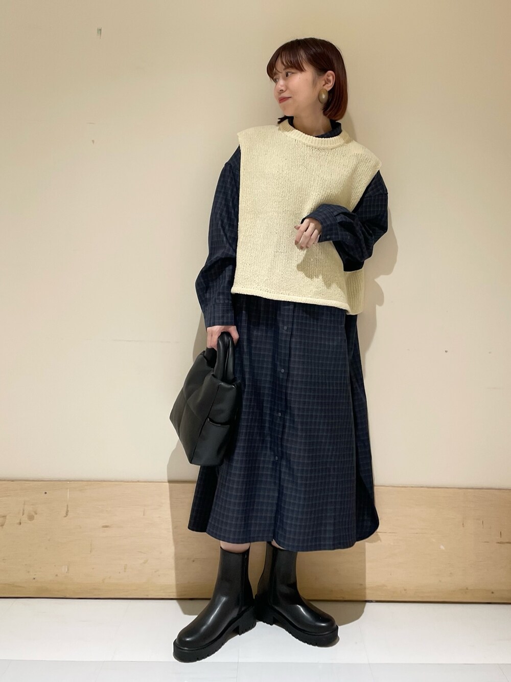 ホワイト系のベスト、グレー系のシャツワンピース、ブラック系のトートバッグを着用したレディースの秋コーディネートの2枚目の写真