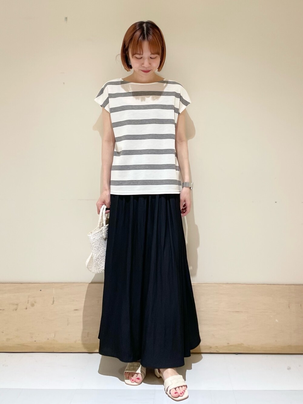 グレー系のTシャツ/カットソー、ホワイト系のハンドバッグ、ホワイト系のサンダルを着用したレディースの春コーディネートの2枚目の写真