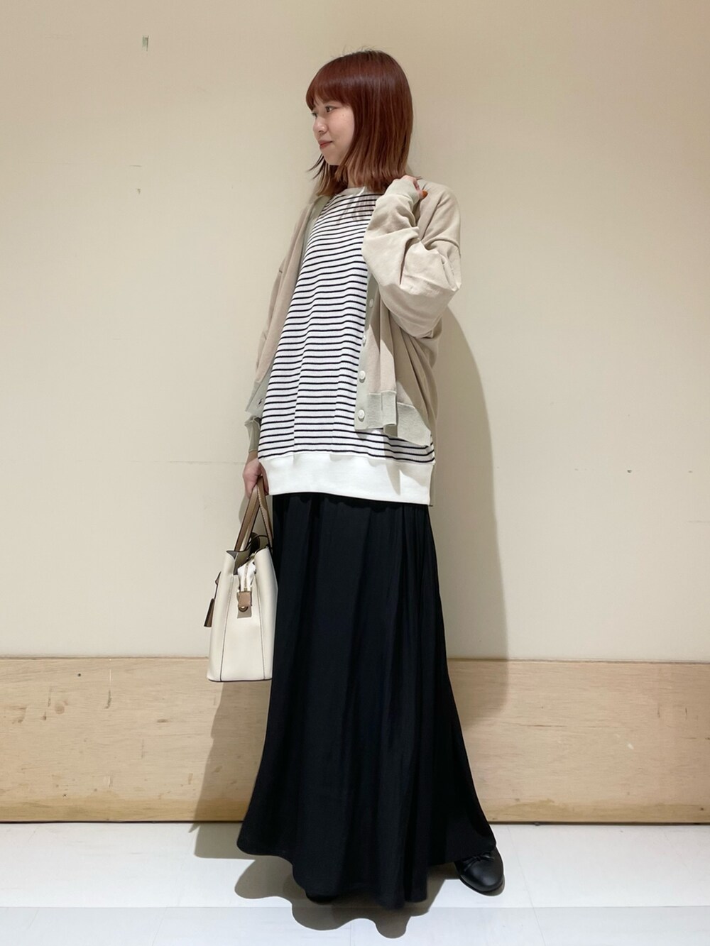 ブラック系のスカート、ホワイト系のTシャツ/カットソー、ベージュ系のカーディガン/ボレロを着用したレディースの春コーディネートの2枚目の写真