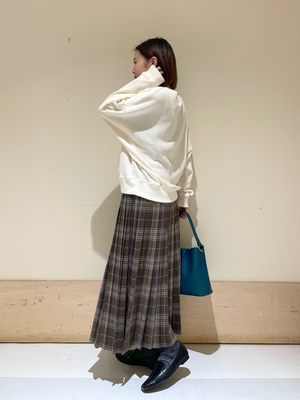 ブルー系のハンドバッグ、ブラック系のローファー、ベージュ系のTシャツ/カットソーを着用したレディースの秋コーディネートの5枚目の写真