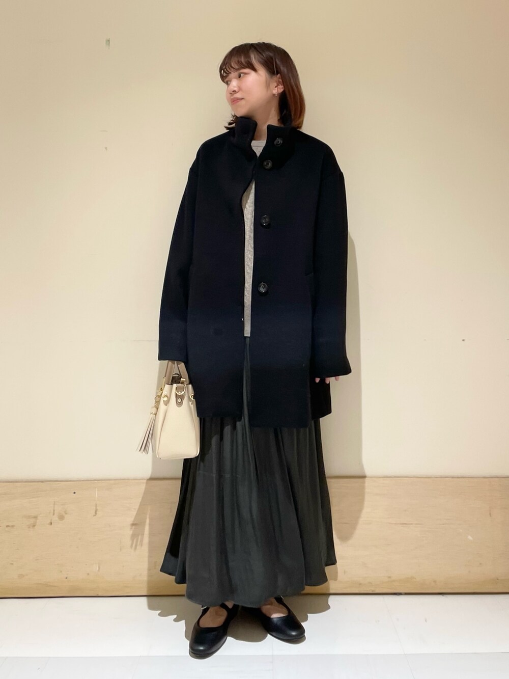 グリーン系のスカート、グレー系のニット/セーター、ブラック系のその他アウターを着用したレディースの冬コーディネートの9枚目の写真