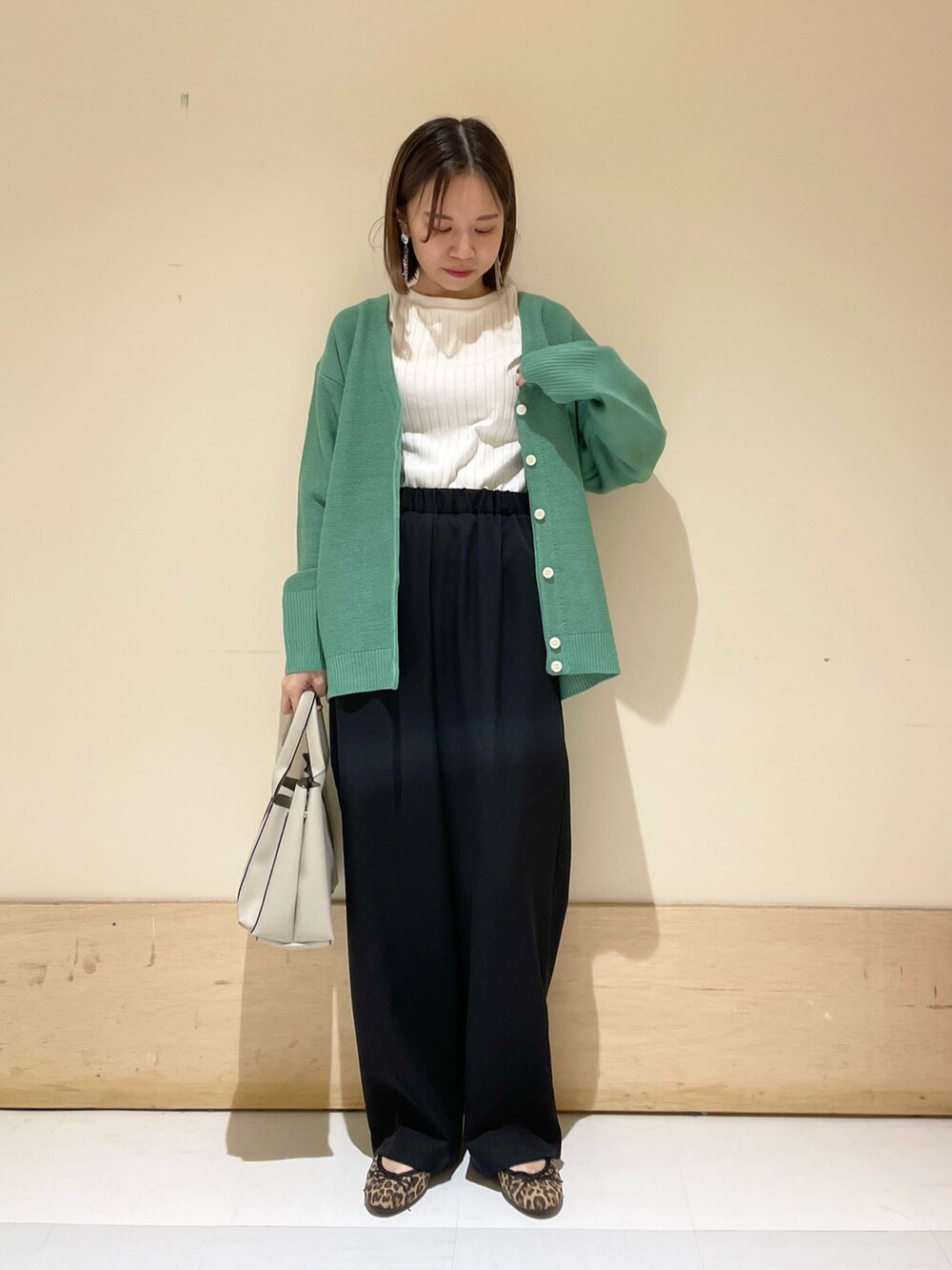 グリーン系のカーディガン/ボレロ、ホワイト系のTシャツ/カットソー、グレー系のトートバッグを着用したレディースの秋コーディネートの2枚目の写真