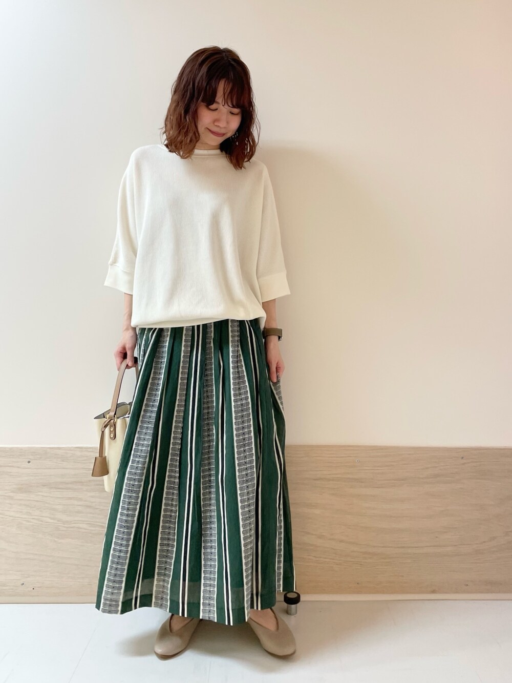 ホワイト系のTシャツ/カットソー、グリーン系のスカート、ベージュ系のパンプスを着用したレディースの春コーディネートの3枚目の写真