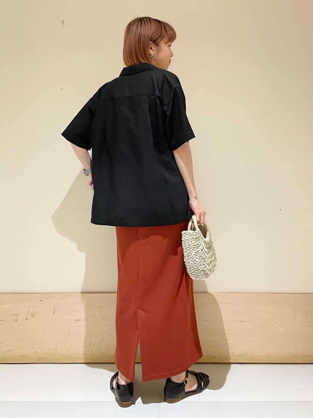 オレンジ系のワンピース、グレー系のかごバッグ、ブラック系のシャツ/ブラウスを着用したレディースの春コーディネートの7枚目の写真