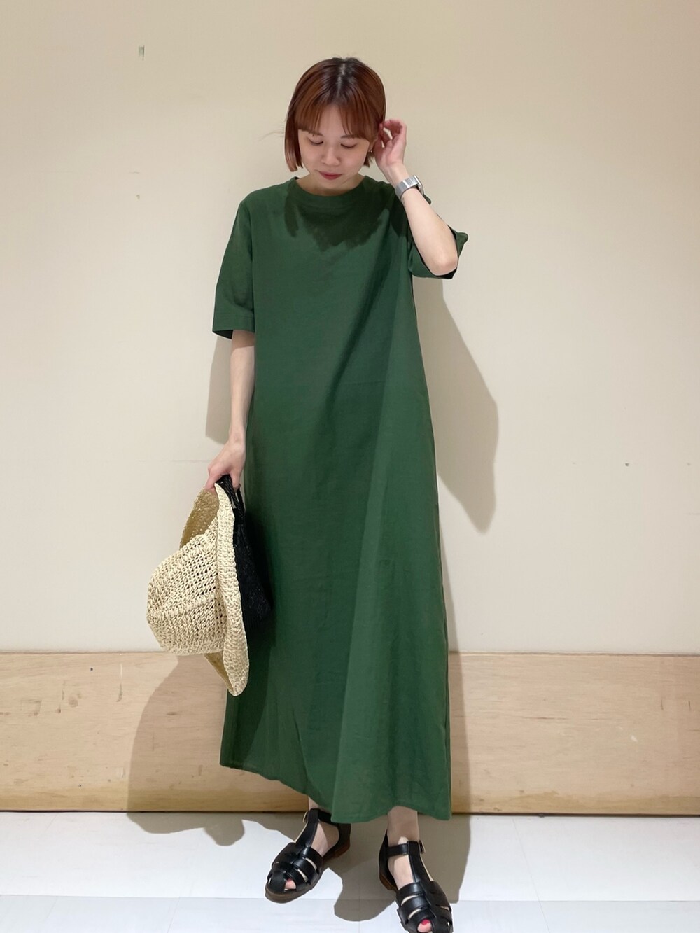 グリーン系のワンピース、ブラック系のサンダル、ブラック系のハンドバッグを着用したレディースの春コーディネートの3枚目の写真