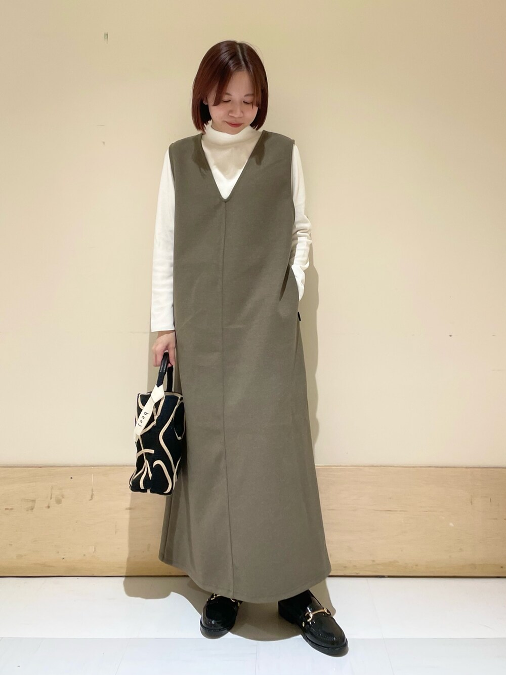 ブラウン系のワンピース、ホワイト系のTシャツ/カットソー、ブラック系のショルダーバッグを着用したレディースの秋コーディネートの4枚目の写真