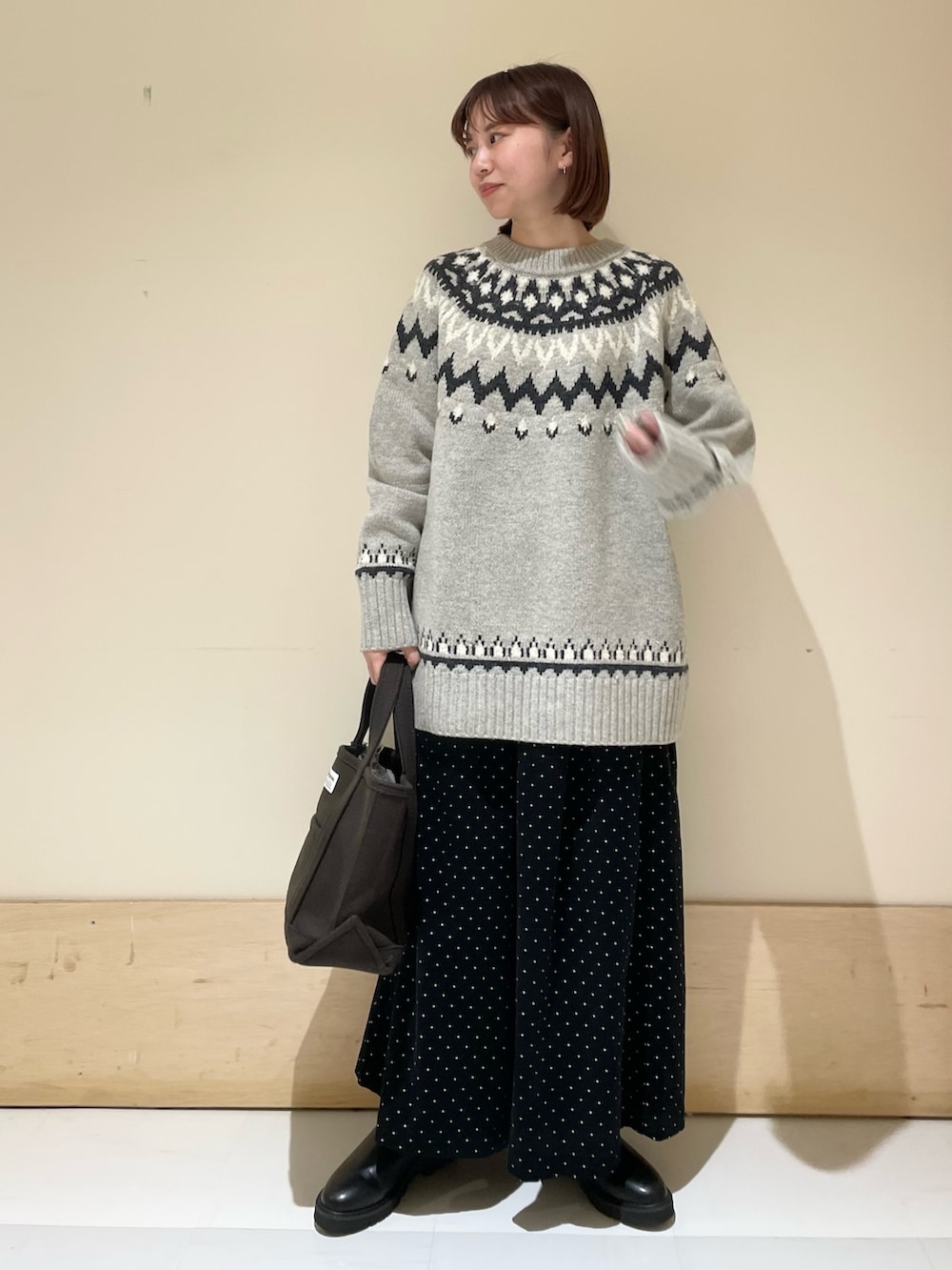 グレー系のニット/セーター、ブラック系のブーツ、ブラウン系のトートバッグを着用したレディースの秋コーディネートの2枚目の写真