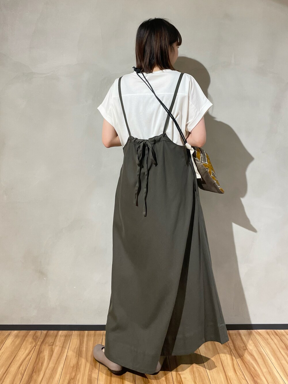 グリーン系のスカート、ホワイト系のTシャツ/カットソー、ブラック系のショルダーバッグを着用したレディースの秋コーディネートの4枚目の写真