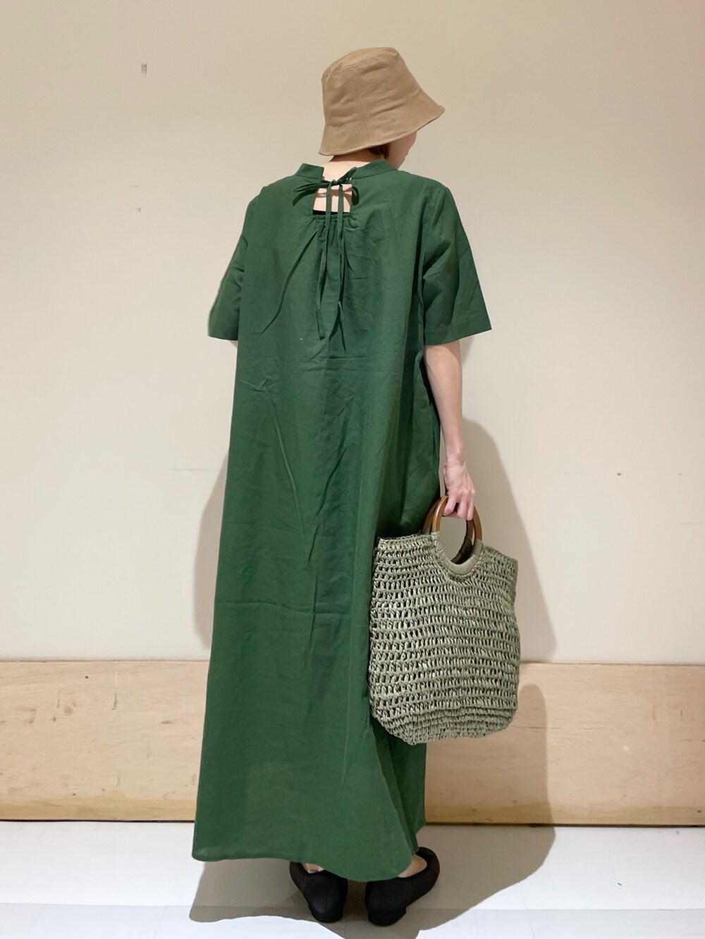 グリーン系のワンピース、ブラック系のバレエシューズ、グリーン系のかごバッグを着用したレディースの春コーディネートの8枚目の写真