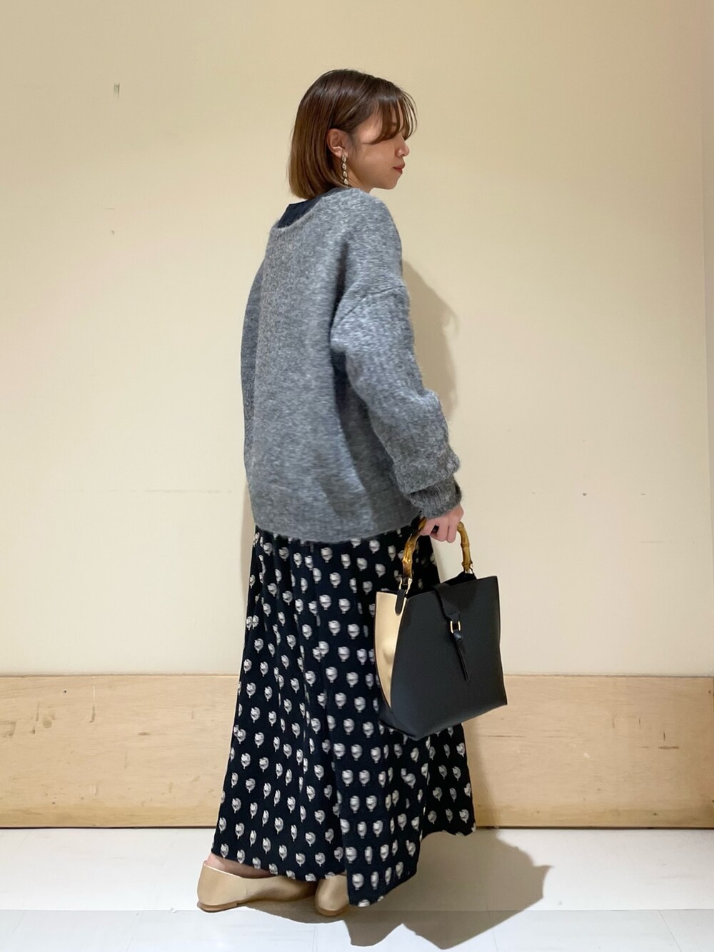 グレー系のニット/セーター、ブラック系のワンピース、ブラック系のハンドバッグを着用したレディースの秋コーディネートの6枚目の写真
