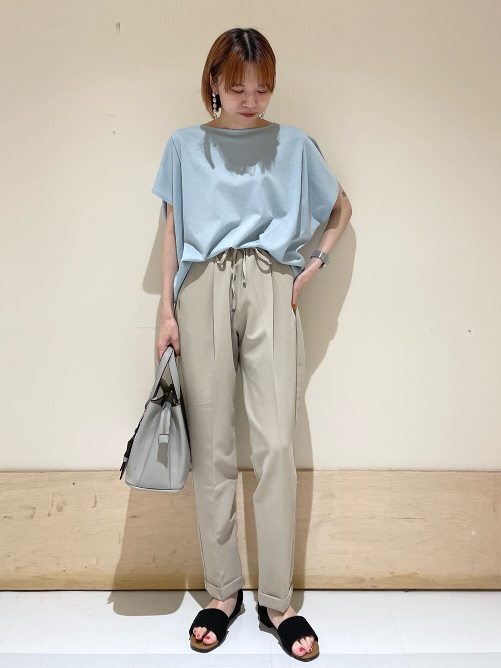 ベージュ系のその他パンツ、ブルー系のTシャツ/カットソー、ブラック系のサンダルを着用したレディースの夏コーディネートの2枚目の写真