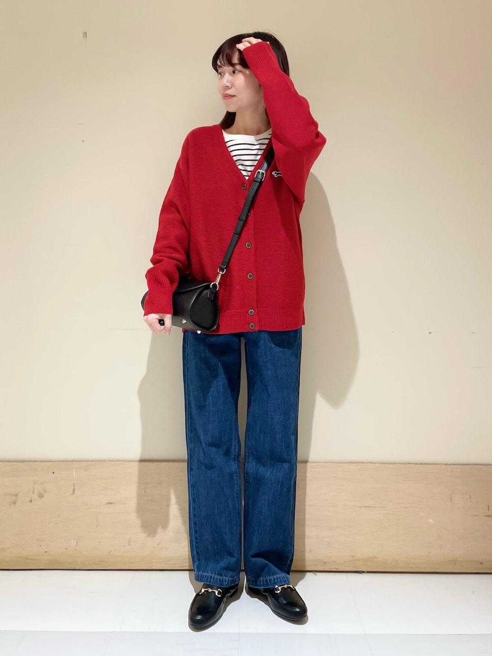 ブラック系のショルダーバッグ、レッド系のカーディガン/ボレロ、ホワイト系のTシャツ/カットソーを着用したレディースの冬コーディネートの2枚目の写真