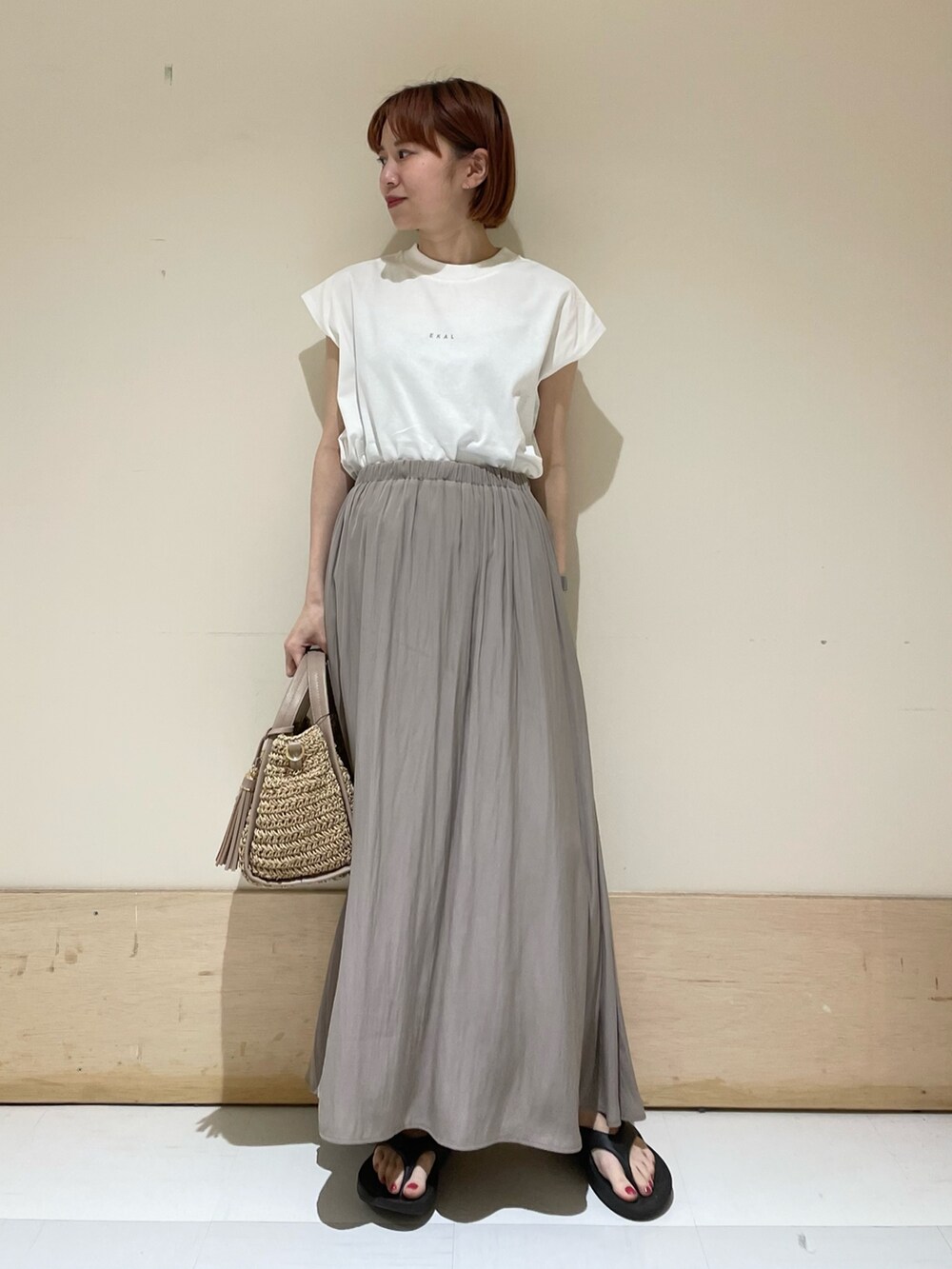 グレー系のスカート、ホワイト系のTシャツ/カットソー、ベージュ系のかごバッグを着用したレディースの春コーディネートの2枚目の写真