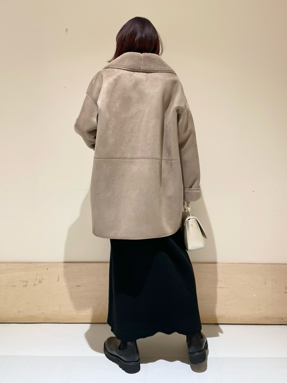 グレー系のムートンコート、ブラック系のワンピース、ゴールド系のショルダーバッグを着用したレディースの冬コーディネートの4枚目の写真