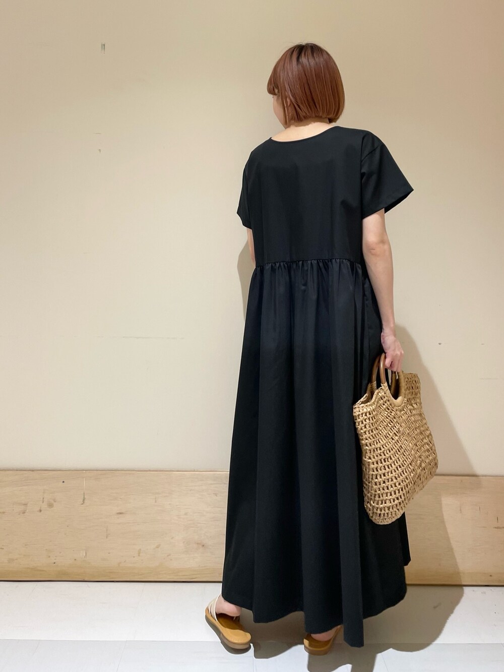 ホワイト系のサンダル、ベージュ系のかごバッグ、ブラック系のワンピースを着用したレディースの春コーディネートの8枚目の写真