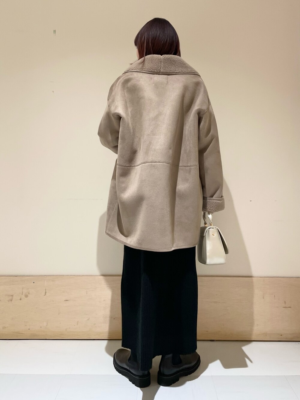 グレー系のムートンコート、ブラック系のワンピース、ゴールド系のショルダーバッグを着用したレディースの冬コーディネートの6枚目の写真