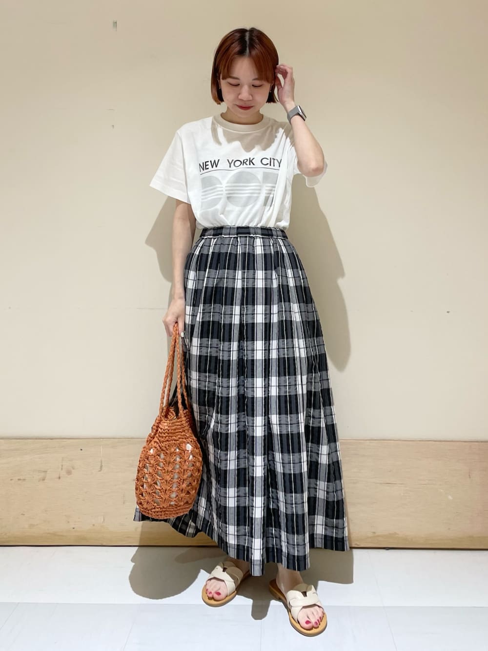 ブラック系のスカート、グレー系のTシャツ/カットソー、ブラウン系のかごバッグを着用したレディースの春コーディネートの3枚目の写真