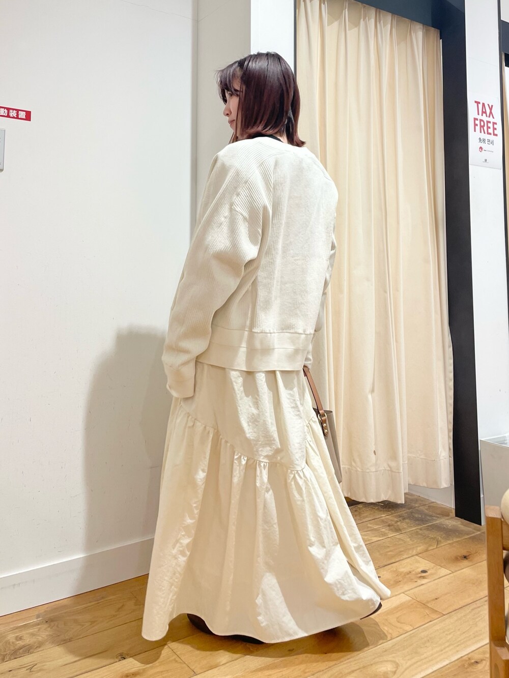 ホワイト系のカーディガン/ボレロ、ブラック系のTシャツ/カットソー、ホワイト系のスカートを着用したレディースの春コーディネートの5枚目の写真
