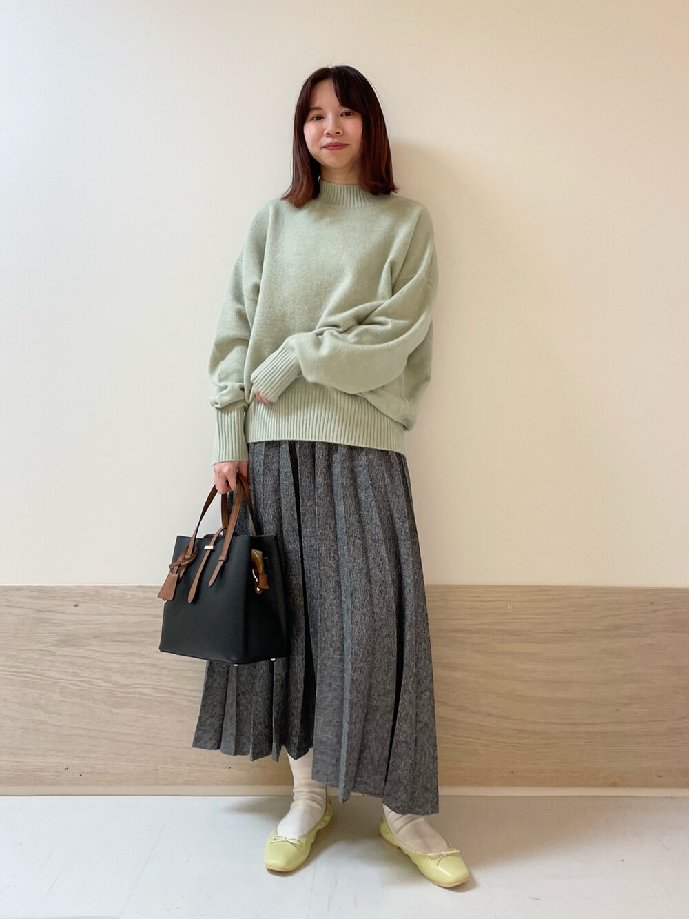 グリーン系のニット/セーター、イエロー系のバレエシューズ、ブルー系のスカートを着用したレディースの冬コーディネートの3枚目の写真