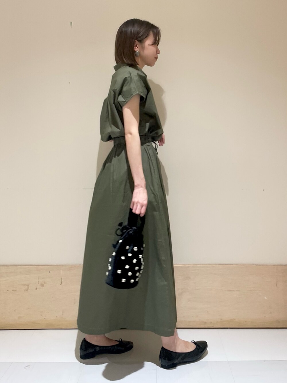 ブラック系のパンプス、ベージュ系のハンドバッグ、グリーン系のワンピースを着用したレディースの夏コーディネートの4枚目の写真