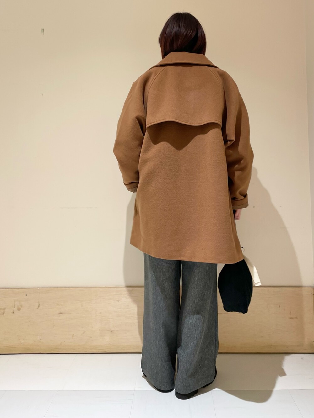 イエロー系のピーコート、グレー系のTシャツ/カットソー、ブラック系のハンドバッグを着用したレディースの冬コーディネートの5枚目の写真