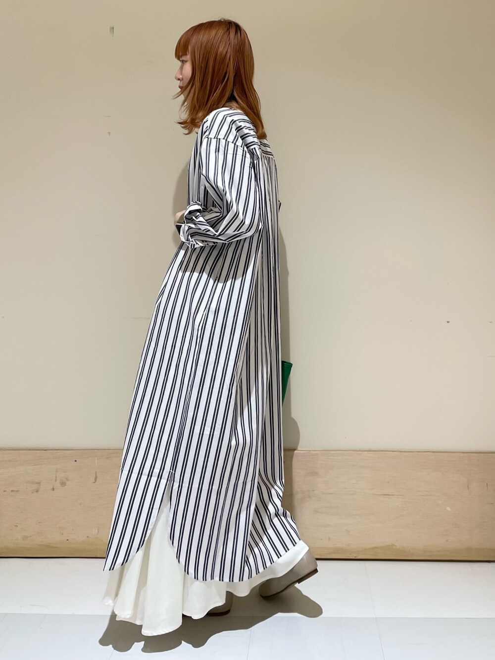 グリーン系のトートバッグ、ベージュ系のパンプス、ブルー系のワンピースを着用したレディースの春コーディネートの4枚目の写真