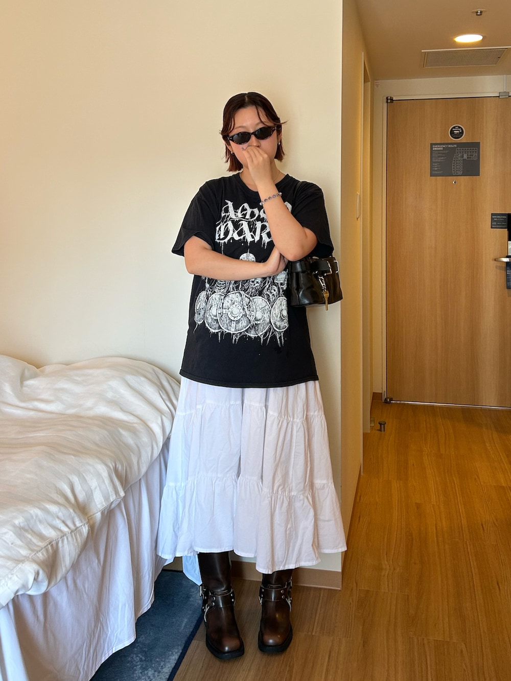 ブラック系のショルダーバッグ、ホワイト系のスカート、ブラウン系のブーツを着用したレディースの秋コーディネートの2枚目の写真