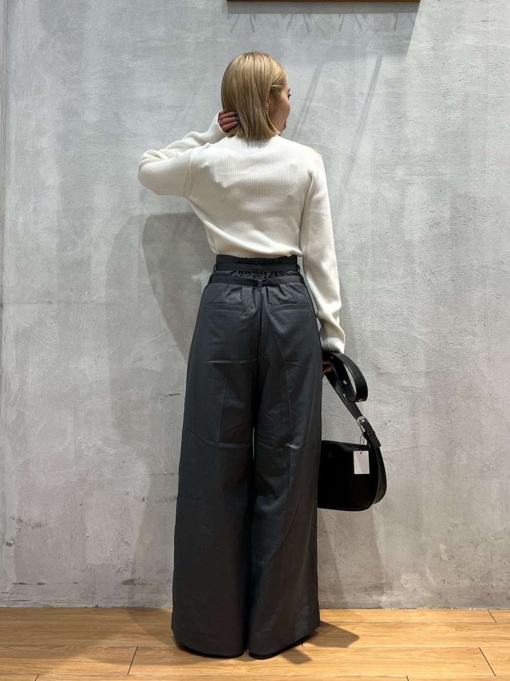 グレー系のスラックス、ホワイト系のトップス、ブラック系のショルダーバッグを着用したレディースの秋コーディネートの4枚目の写真