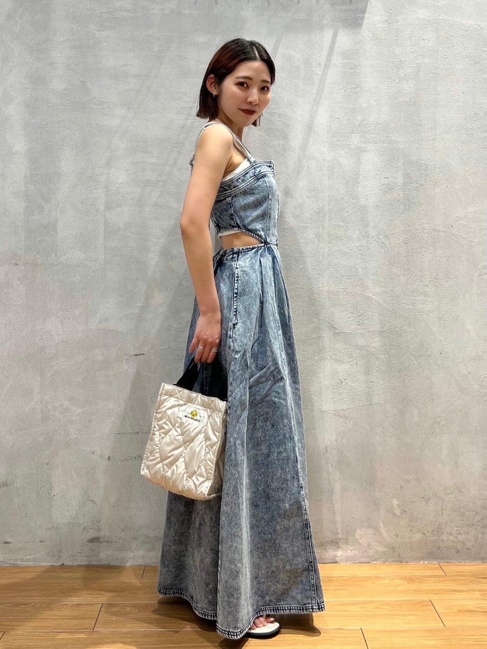 ホワイト系のショルダーバッグ、ブルー系のジャンパースカート、ホワイト系のサンダルを着用したレディースの夏コーディネートの3枚目の写真