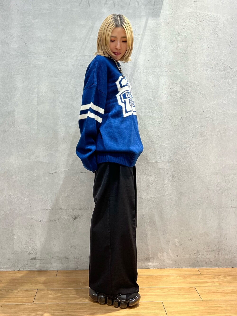 ブルー系のニット/セーター、ブラック系のスラックスを着用したレディースの秋コーディネートの2枚目の写真