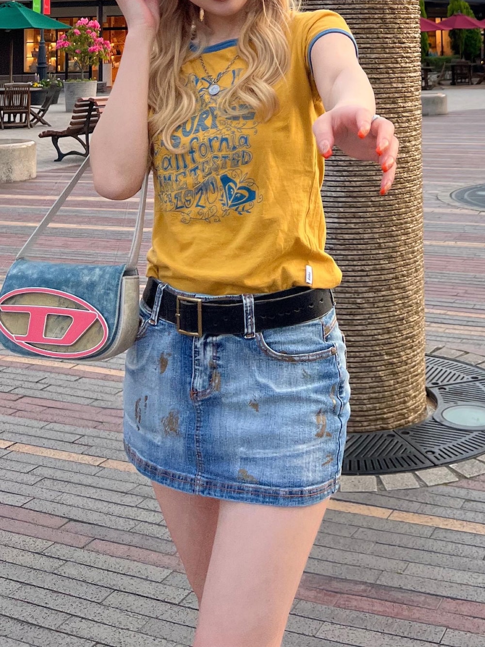 イエロー系のTシャツ/カットソー、ブルー系のデニムスカート、ブルー系のショルダーバッグを着用したレディースの春コーディネートの4枚目の写真