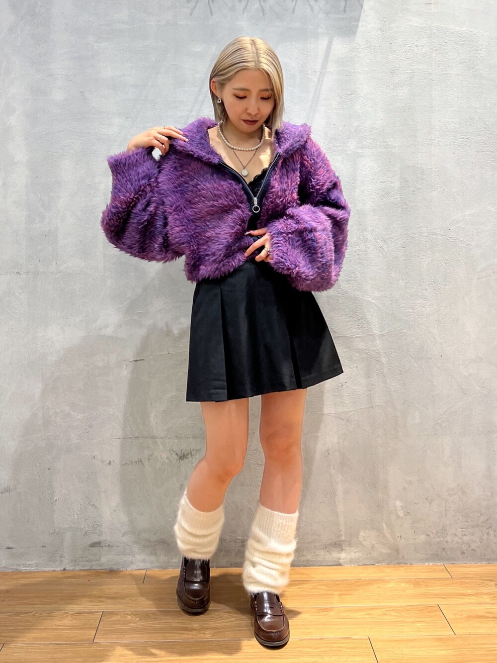 パープル系のパーカー、ブラック系のスカート、ホワイト系のレッグウォーマーを着用したレディースの秋コーディネートの2枚目の写真